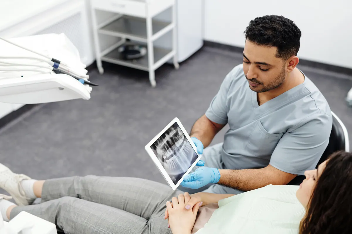 Dentiste expliquant une radiographie à une patiente sur une tablette